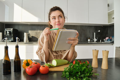 Portrait of smiling young woman using mobile phone while sitting at home
