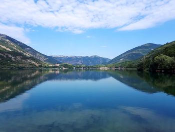 Scenic view of lake by mountains against sky