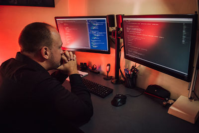 Tired man sitting in front of computers in office