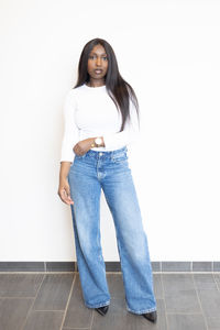 Portrait of young woman standing against wall