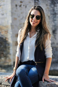 Portrait of young woman wearing sunglasses while sitting outdoors