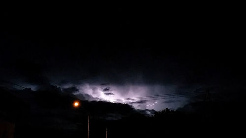 Low angle view of silhouette lights against sky at night