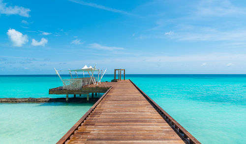 Pier over sea against blue sky