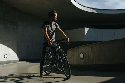 Full length of young man with bicycle standing against wall