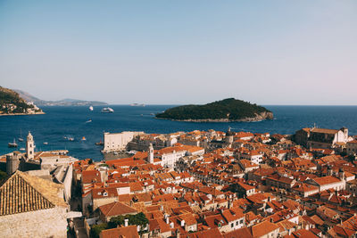 High angle view of townscape by sea against clear sky