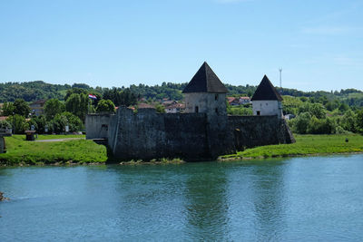 Building by river against clear blue sky