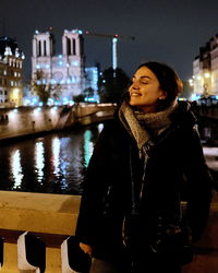 Portrait of young woman standing against river