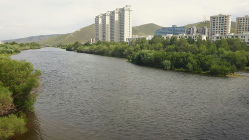 River amidst buildings in city against sky