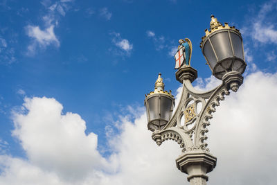 Low angle view of statue of street light against cloudy sky