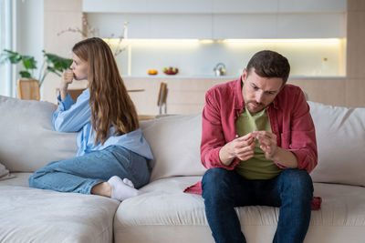 Young woman using phone while sitting on sofa at home