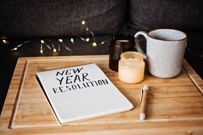 Goals for the 2023 year, new year resolution text in open notepad near cup and candles at sofa in