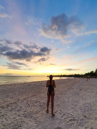 Man standing on beach against sky during sunset