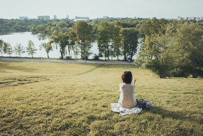 Rear view of woman sitting on field