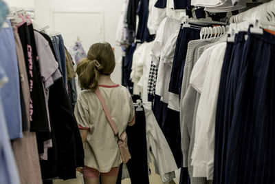 A little girl chooses a school uniform in a store.