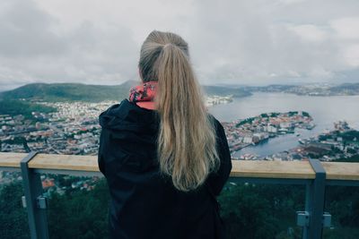 Rear view of woman standing by railing against sky