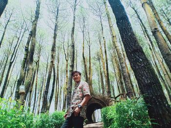 Young man sitting on tree trunk in forest