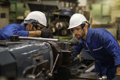 Engineers working together over machinery at factory