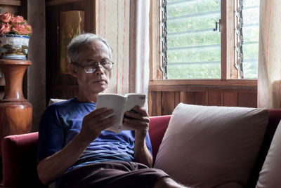 Man using mobile phone while sitting on sofa at home