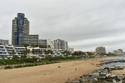 View of city at beach against cloudy sky