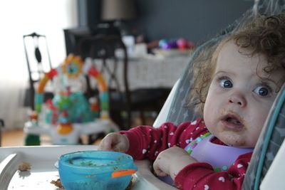 Portrait of cute girl sitting in chair eating 