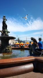 Seagull flying over statue