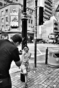 Man photographing woman by street