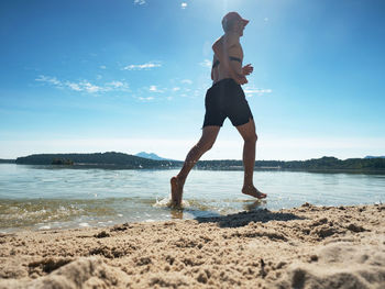 Runner run in water at beach, water drops refreshing his body. training with heart rate monitor