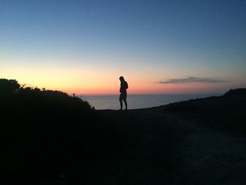 Silhouette man standing on beach against sky during sunset