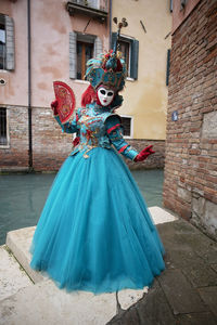 Portrait of woman in carnival costume standing by canal in city