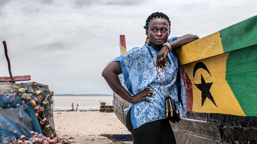 African woman from ghana with blue dress stands by a fishing boat on a beach in ghana west africa