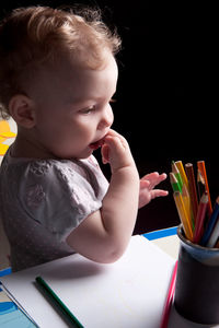 Cute boy looking away while sitting on table