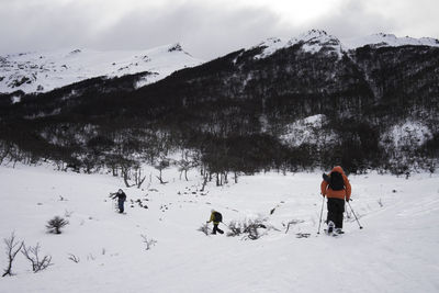 People on snow covered field against snowcapped mountains