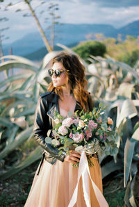 Portrait of young woman standing by plants