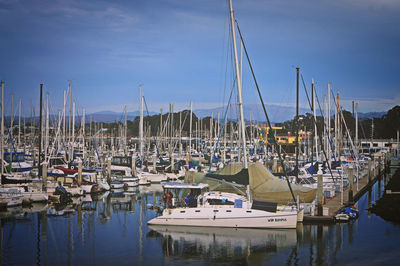 Boats moored at harbor against sky