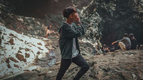 Man covering face while standing outdoors