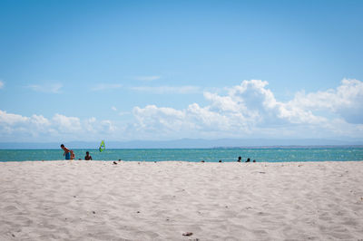 People on beach against blue sky