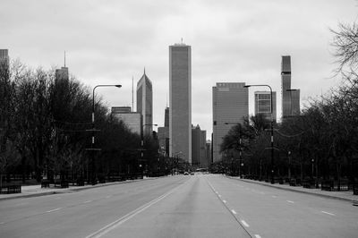 Road by buildings against sky in city