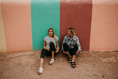 Friends sitting against wall