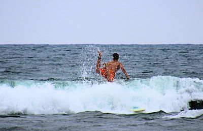 Man surfing on sea against clear sky