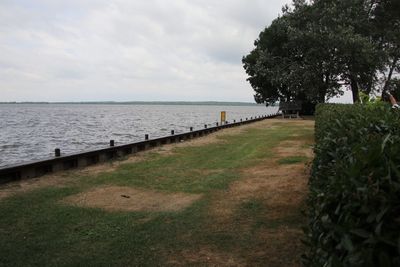 Footpath by sea against sky