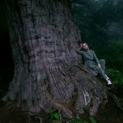 Full length of young woman on tree trunk