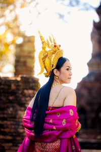 Rear view of woman wearing traditional clothing and crown looking away at temple