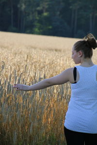 Rear view of young woman touching crops on farm