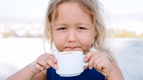 Close-up portrait of cute girl drinking coffee