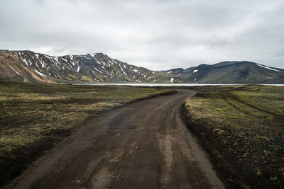 Road leading towards mountains against sky