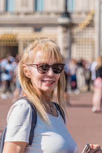 Portrait of a mature blonde woman with sunglasses looking at the camera. unfocused buckingham palace