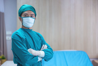 Portrait of a male surgeon in an operating room with a team of doctors in the background.