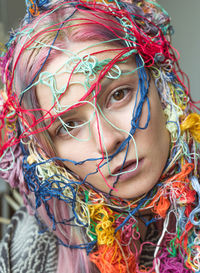 Close-up portrait of woman with colorful threads on face