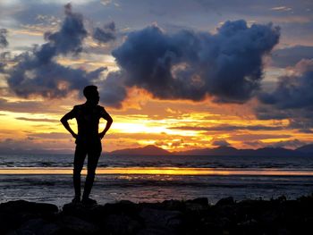 Silhouette man standing on beach against sky during sunset