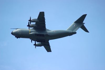 Low angle view of airplane against clear blue sky